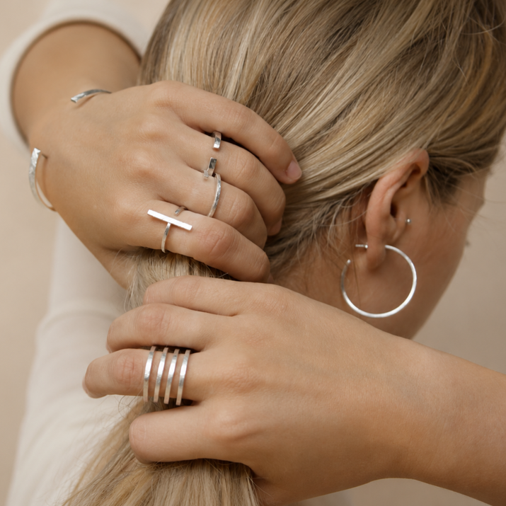 Conjunto de anillos y pendientes plateados de joyería artesanal